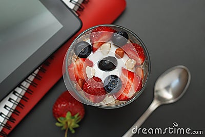 Breakfast for health, fresh strawberries, Blueberies, with oatmeal Black office table. Tablet, laptop and Notebook. Top view. Copy Stock Photo