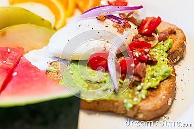 Breakfast for a healthy lifestyle. Avocado toast, poached egg and sliced fruit Stock Photo