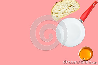 Breakfast ingredients slice of white bread cracked raw egg with bright yellow yolk frying pan on pink background Stock Photo