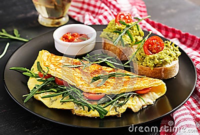 Breakfast. Omelette with tomatoes, cheese, green arugula and toasts with avocado cream Stock Photo