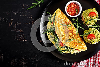 Breakfast. Omelette with tomatoes, cheese, green arugula and toasts with avocado cream Stock Photo