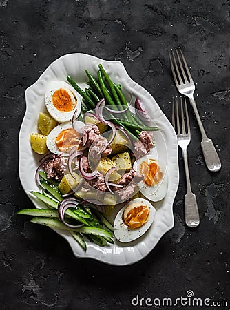 Breakfast plate - boiled eggs, potatoes, string beans, red onion, cucumber, canned tuna salad on a dark background, top view Stock Photo