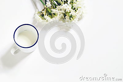 Breakfast scene. Spring composition with mug of milk and bouquet of narcissus, daffodil flowers on white wooden table Stock Photo