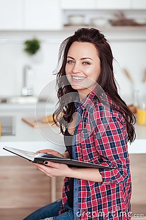 Breakfast - Smiling woman reading book in white kitchen, fresh orange juice Stock Photo