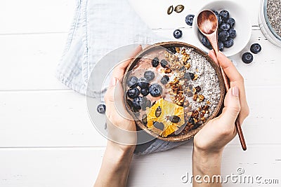 Breakfast smoothie bowl with chia pudding, berries and granola in a coconut shell on white wooden background Stock Photo
