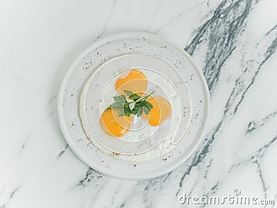 Breakfast is three eggs fried on a white plate on a white marble background. Stock Photo