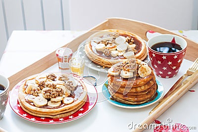 Breakfast tray with pancakes with bananas, maple syrup and nuts, cup of coffee and honey Stock Photo