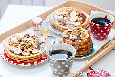 Breakfast tray with pancakes with bananas, maple syrup and nuts, cup of coffee and honey Stock Photo