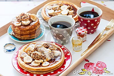 Breakfast tray with pancakes with bananas, maple syrup and nuts, cup of coffee and honey Stock Photo