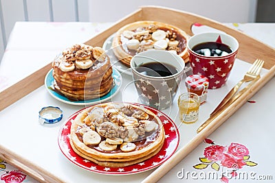 Breakfast tray with pancakes with bananas, maple syrup and nuts, cup of coffee and honey Stock Photo