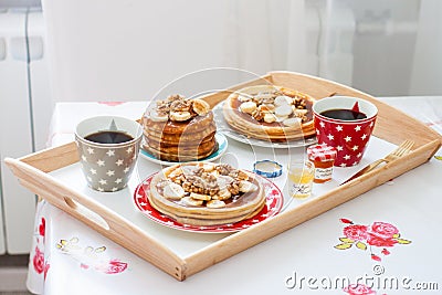 Breakfast tray with pancakes with bananas, maple syrup and nuts, cup of coffee and honey Stock Photo