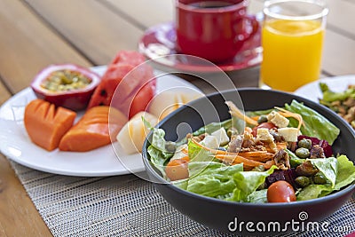 Breakfast. Vegetable salad, fruits such as watermelon, papaya, melon, passion fruit, orange juice and coffee. placed on a gray Stock Photo