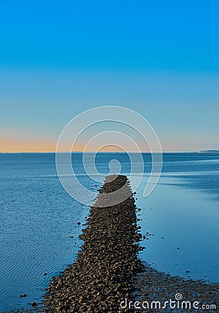 Breakwater made of gravel stones in the blue North Sea against a blue sky, abstract, calm, meditative Stock Photo