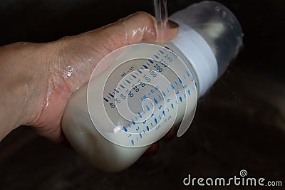 Breast milk in the bottle thawing under running water Stock Photo