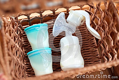 Breast pump and containers with breast milk for baby in straw basket. Stock Photo