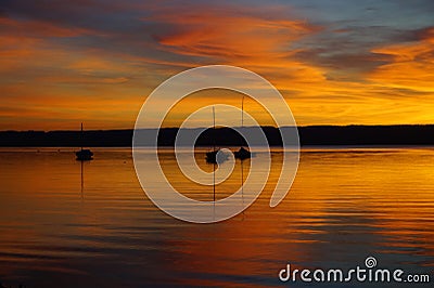 a breathtaking burning sunset on lake Ammersee (Germany) with sailing boats resting on the water Editorial Stock Photo