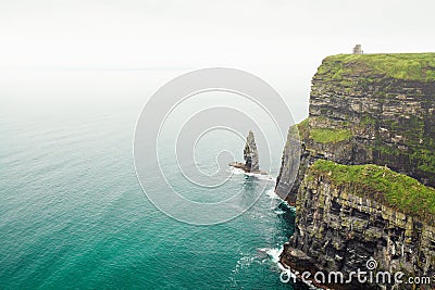 Breathtaking high angle shot of a green cliff next to the ocean with turquoise water Stock Photo