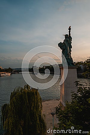 Breathtaking image of the iconic Statue of Liberty in Paris against a picturesque sunset sky Editorial Stock Photo