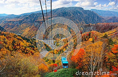 A breathtaking view from a cable car of Kurodake Ropeway flying over colorful autumn forests on the mountainside in Sounkyo Gorge Stock Photo