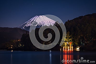 Breathtaking view of the snowy mount Fuji behind the illuminated tori gate at the Ashi lake shore Stock Photo