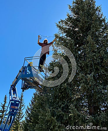 City worker standing in the Genie aerial lift installing Christmas lights Editorial Stock Photo