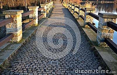 Breeding pond dam. water flows under a stone bridge with several arches. bridge on the crown of the dam with canals for drainage o Stock Photo