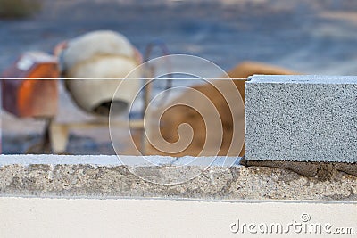 Breeze block wall construction with string line and cement mixer Stock Photo