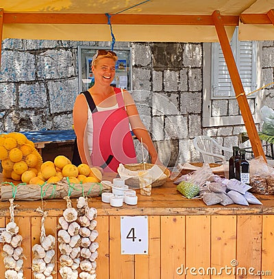 Brela. Croatia - June 25, 2019: Fair, Beautiful smiling woman stands behind the counter and sells seasonal fruits and vegetables Editorial Stock Photo