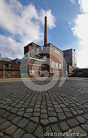 Bremen, Germany - April 15th, 2018 - Beck`s Brewery buildings with cobblestone street in the foreground wide angle shot Editorial Stock Photo
