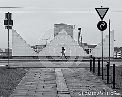 Bremen, Germany - December 31st, 2018 - Street scene with solitary woman walking on a sidewalk in front of a large white sculpture Editorial Stock Photo