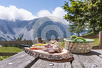 Brettljause on wooden table with view to mountain range Karawanks Stock Photo