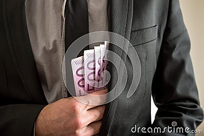 Bribery concept - businessman placing cash in his pocket Stock Photo