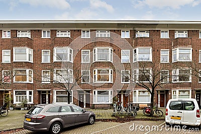 a brick apartment building with cars parked in front Editorial Stock Photo