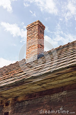 Brick chimney on tile roof of an old wooden house Stock Photo