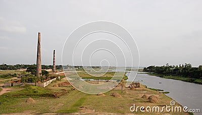 Brick kilns on a greenfield beside Titas river with a bunch of haystack photoshoots. Greenfield and tree horizon with two brick Stock Photo