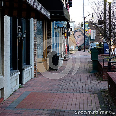 Brick sidewalk in Jonesboro, Arkansas, with a graffiti mural of a woman in the background Editorial Stock Photo