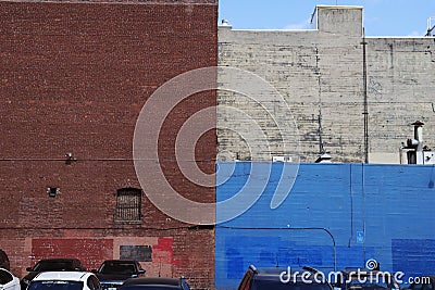 Brick walls painted in white, blue and brown behind a parking lot Editorial Stock Photo