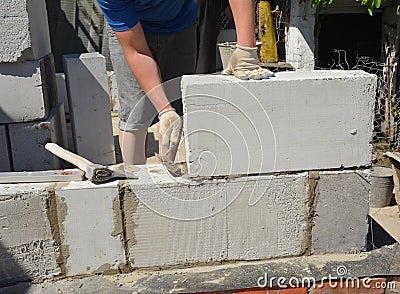 Bricklayer builder laying autoclaved aerated concrete blocks, aac for new house wall. Autoclaved aerated concrete blocks walling Stock Photo