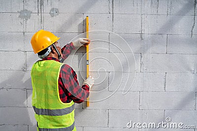 Bricklayer builder using the water level, check the inclination of autoclaved aerated concrete blocks. Walling, installing bricks Stock Photo