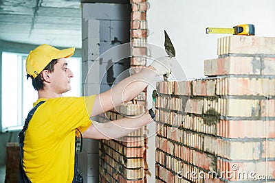 Bricklayer builder worker laying bricks wall Stock Photo
