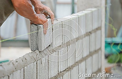 Bricklayer hands installing brick block on construction site Stock Photo