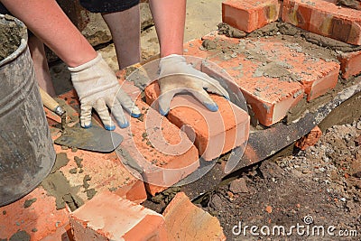 A bricklayer is laying the first row of bricks on a concrete foundation or footing above a damp proof course, a layer of Stock Photo