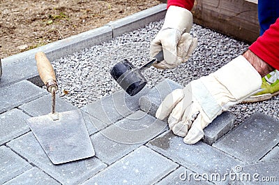 Bricklayer places concrete paving stone blocks for building up a Stock Photo