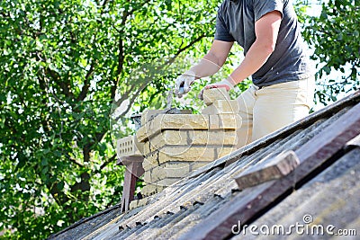 Bricklayer repair brick chimney on asbestos house rooftop Stock Photo