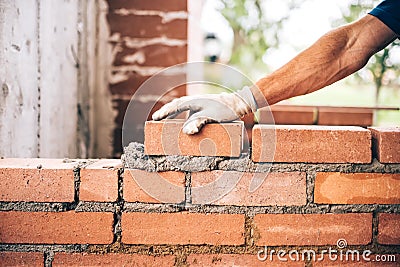 Bricklayer worker placing bricks on cement while building exterior walls, industry details Stock Photo