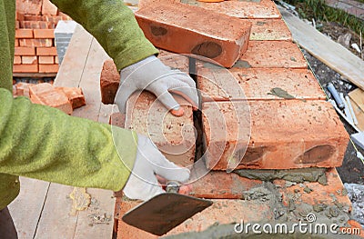 Bricklayers hands in masonry gloves bricklaying on House Construction Site. Bricklaying, Brickwork. Stock Photo
