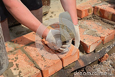 Bricklayers hands with in masonry trowel bricklaying new house wall on foundation Stock Photo