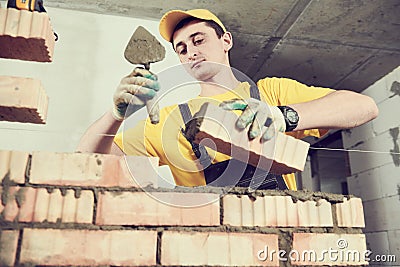 Bricklayer builder worker laying bricks wall Stock Photo