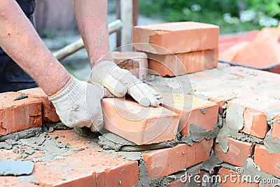 Bricklaying house wall, masonry. Bricklayer hands in masonry gloves bricklaying house wall Stock Photo