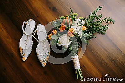 Bridal bouquet of white and orange roses, eringyum, ammi, boxwood branches, alstroemeria with white ribbons and shoes of Stock Photo